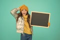 Smiling girl wear winter outfit show blank chalkboard copy space. Informing kids community. Kid with blackboard