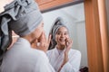 smiling girl wearing bathrobe and towel with fingers touching cheeks reflecting