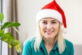 Smiling girl wearing Santa hat having video calling family by webcam. Woman with laptop sitting on kitchen at home using Royalty Free Stock Photo
