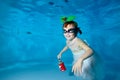 A smiling girl in a white dress at the bottom of a children`s pool with a Christmas toy. Decorations in the form of