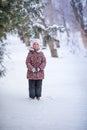 Smiling girl with white fur hat like a cat. Winter snowy background and gteen trees