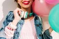 Smiling girl with wristwatch and cute handmade accessories holding new big turquoise headphones. Charming young woman Royalty Free Stock Photo