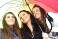 Smiling girlfriends under umbrella