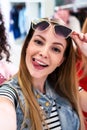 Smiling girlfriends wearing stylish sunglasses having fun time taking selfie with mobile phone while doing shopping in