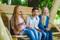 Smiling girls and boy having fun at playground. Children playing outdoors in summer. Teenagers on a swing. Royalty Free Stock Photo