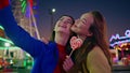 Smiling girls making selfie at illuminated funfair closeup. Two friends hugging Royalty Free Stock Photo