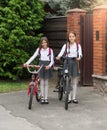 Smiling girls in school uniform with bicycles in front of house