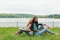 Smiling girls sitting back to back on grass Royalty Free Stock Photo