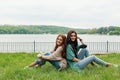 Smiling girls sitting back to back on grass Royalty Free Stock Photo