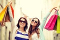 Smiling girls in sunglasses with shopping bags Royalty Free Stock Photo