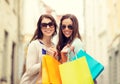 Smiling girls in sunglasses with shopping bags Royalty Free Stock Photo