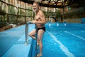 Smiling glad senior man swimming trunks getting out from pool