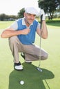 Smiling golfer kneeling on the putting green Royalty Free Stock Photo