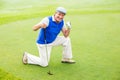 Smiling golfer kneeling on the putting green Royalty Free Stock Photo