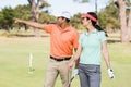 Smiling golfer man pointing while standing by woman Royalty Free Stock Photo