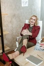 Smiling good-looking lady with blue eyes resting on white armchair