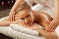 Smiling good-looking naked girl lying on white towels while massage master