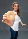 Smiling gorgeous young woman enjoying showing a fresh yummy donut