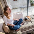 Smiling gorgeous young woman sitting on comfortable sofa with breakfast