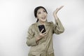 Smiling government worker woman holding her smartphone and pointing to copy space above her. PNS wearing khaki uniform