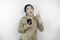 Smiling government worker woman holding her smartphone and pointing to copy space above her. PNS wearing khaki uniform