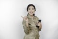Smiling government worker woman holding her smartphone and pointing to copy space beside her. PNS wearing khaki uniform