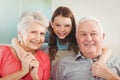 Smiling granddaughter embracing her grandparents in living room Royalty Free Stock Photo