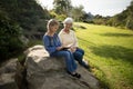 Smiling granddaughter and grandmother reading book in garden