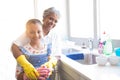 Smiling granddaughter and grandmother wearing kitchen gloves in kitchen