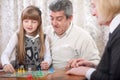 Smiling grandfather, grandmother and granddaughter playing board