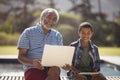 Smiling grandfather and grandson sitting together on bench with laptop and digital tablet Royalty Free Stock Photo