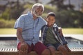 Smiling grandfather and grandson sitting together on bench Royalty Free Stock Photo