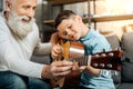 Smiling grandfather showing grandson how to play guitar Royalty Free Stock Photo