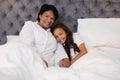 Smiling grandmother and granddaughter relaxing on bed at home Royalty Free Stock Photo