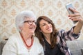 Smiling grandmother and granddaughter taking selfie photo on smart phone. Royalty Free Stock Photo