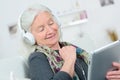 Smiling grandmother with headphones listen to music