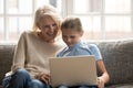 Smiling grandmother and teen granddaughter use laptop Royalty Free Stock Photo