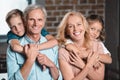 smiling grandparents and grandchildren hugging and looking