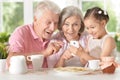 Smiling grandparents with granddaughter using smartphone