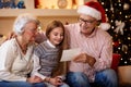 Smiling grandparents with granddaughter watching photo and share