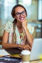 Smiling graphic designer sitting with hand on chin in office