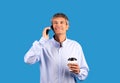 Smiling gray haired man talking on cellphone on blue background