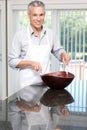 Smiling grey hair man tossing salad in apron