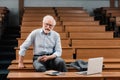 smiling grey hair professor sitting in empty