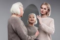 Smiling grey-haired senior woman enjoying her appearance in mirror reflection