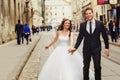 Smiling groom holds bride`s hand while they run along the tramwa Royalty Free Stock Photo