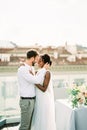 Smiling groom hugging bride on the terrace of the house next to the table Royalty Free Stock Photo