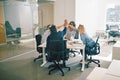 Group of laughing coworkers high fiving during an office meeting