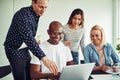 Smiling group of diverse work colleagues working with a laptop Royalty Free Stock Photo