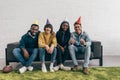 smiling group of young multiethnic friends in party hats sitting